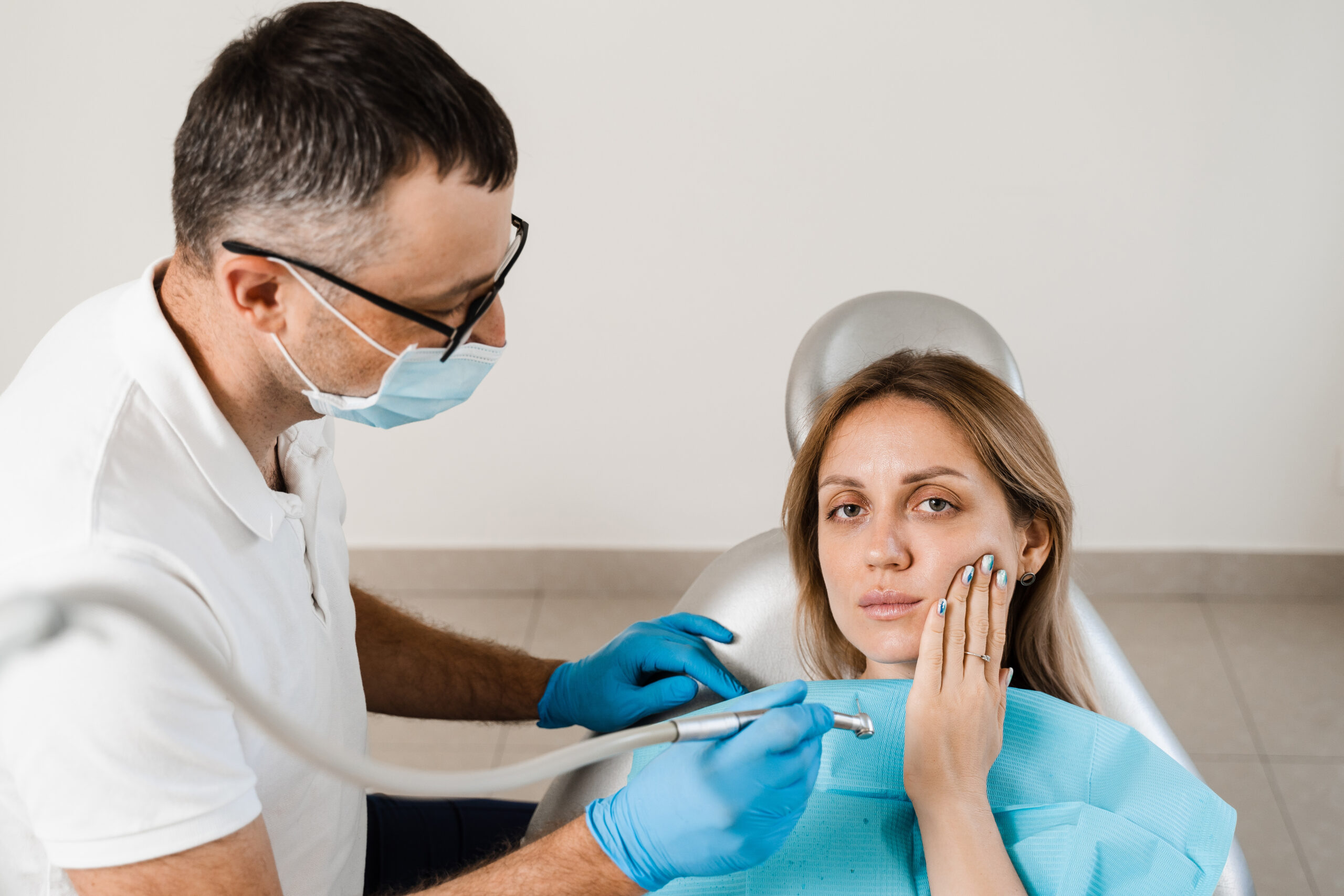 adult-woman-with-dentist-in-hospital-workplace-2026-04-05-00-00-32-utc - Alachua Dental Dentist in mask and gloves examines a patient in a dental chair with dental tools to perform a checkup.
